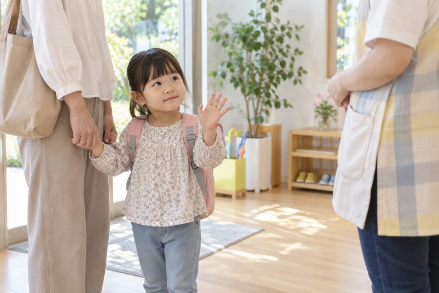 保護者と手をつなぎ、スタッフに手をふる女の子